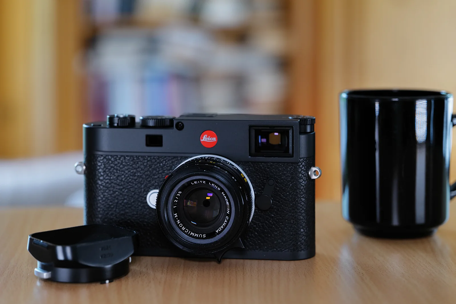 Schwarze Leica M11 mit Leica M Objektiv auf einem Holztisch